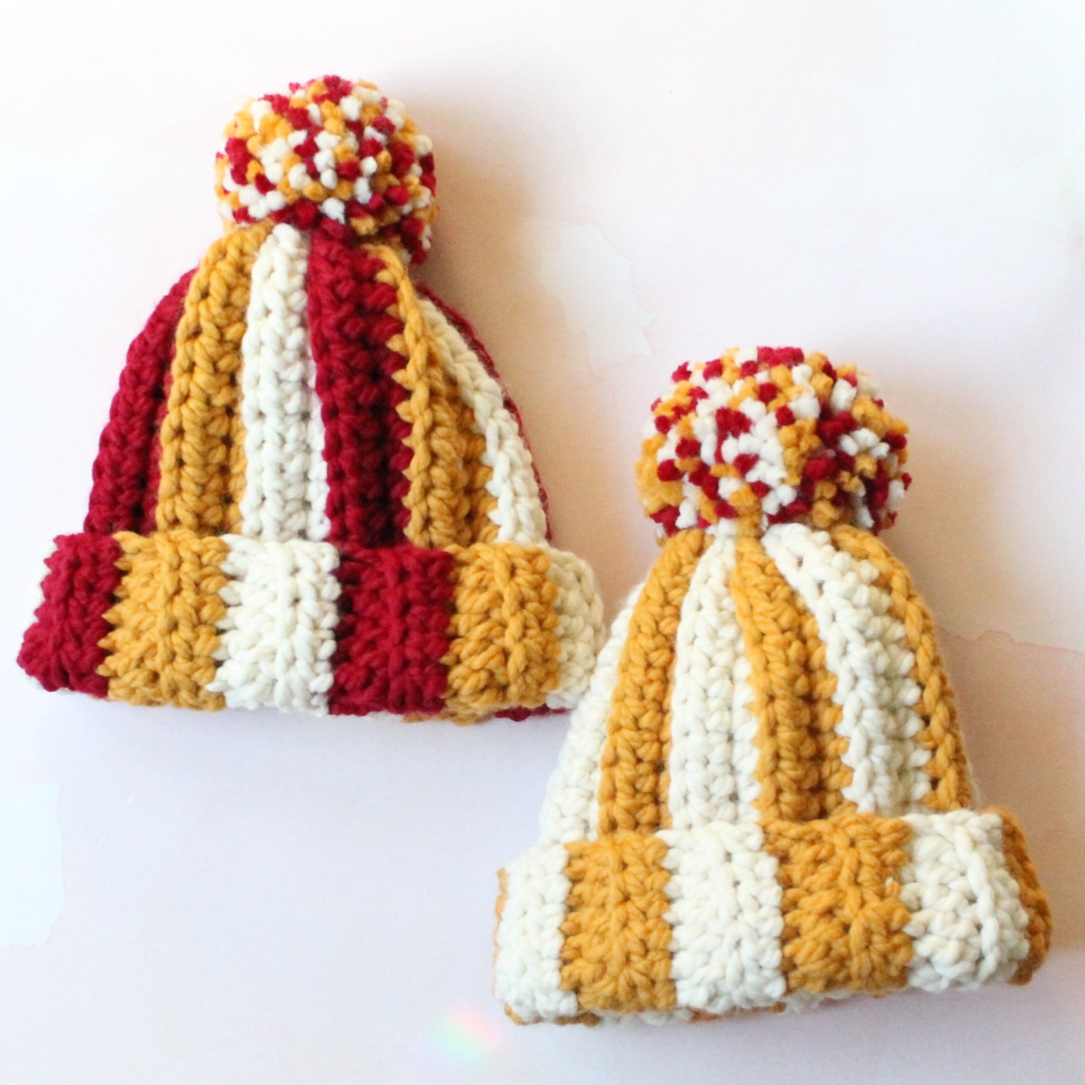 Two crochet hats in red, yellow, and white in support of the Kansas City Chiefs